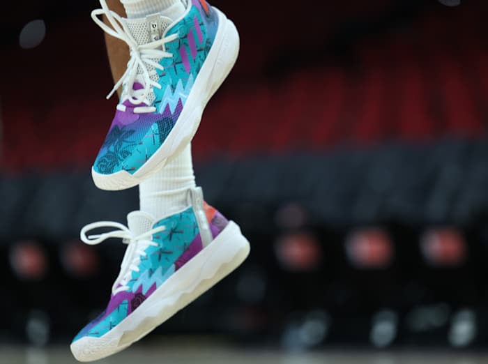 View of teal and purple Adidas Dame shoes.